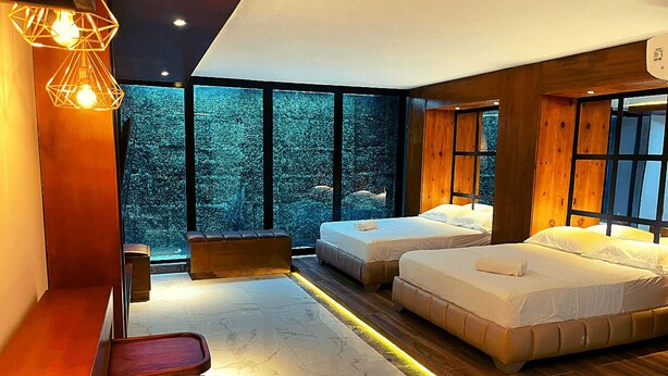 A modern bedroom with two beds, a seating area, and large windows offering a view of trees. - Calle 76 Estudio by Caribecheap (Barranquilla)