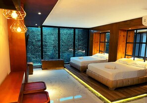 A modern bedroom with two beds, a seating area, and large windows offering a view of trees. - Calle 76 Estudio by Caribecheap (Barranquilla)