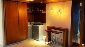 A compact kitchen with a built-in stove, a small refrigerator, and a bar area with stools. - Calle 76 Estudio by Caribecheap (Barranquilla)