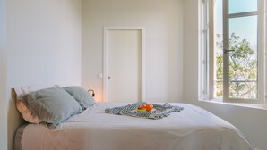 A bedroom with a bed, pillows, a blanket, and a window with a view of trees. - Bright, quiet apartment in the heart of Biarritz (Biarritz)