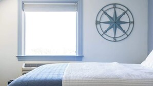Une chambre à coucher avec un lit, une fenêtre et un décor mural en forme de boussole.