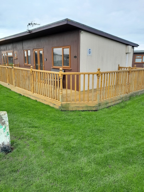 A single-story building with a wooden deck and a fenced area.