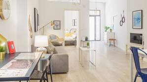 Uma sala de estar moderna com área de jantar, sofá, mesa de centro e televisão.