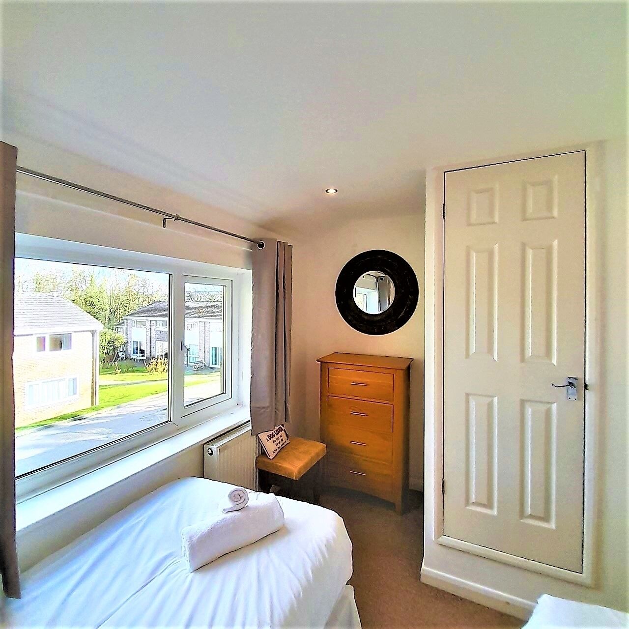 A bedroom with a bed, a dresser, a mirror, and a door.