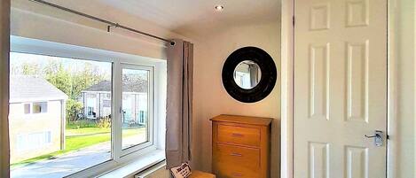 A bedroom with a bed, a dresser, a mirror, and a door.