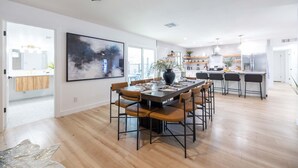 A spacious kitchen with a dining area, wooden flooring, and a large window.