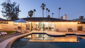 A residential property with a swimming pool, outdoor seating, and a well-lit patio area.