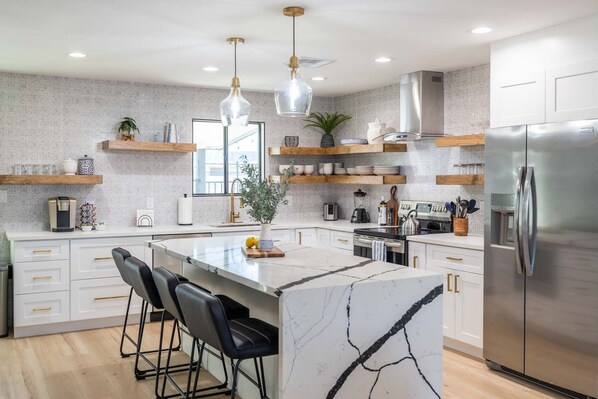 A modern kitchen with a large island, stainless steel appliances, and wooden shelves. - Urban ASU Dreamland with Heated Pool and 3 Baths! (Tempe)