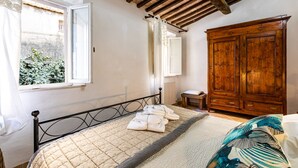 Een slaapkamer met een bed, een houten garderobe en een raam met gordijnen.