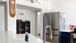 Une cuisine moderne avec un plan de travail blanc, des appareils en acier inoxydable et un mur d’accent en bois.