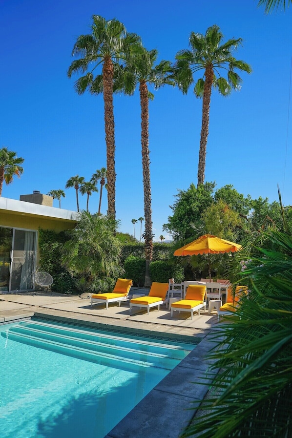 Relax by the pool surrounded by lush greenery and modern architecture.