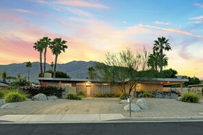 Situated in a hilly area, this property offers a scenic backdrop with mountains visible in the distance.