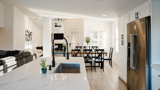A modern kitchen with a marble countertop, stainless steel refrigerator, and a dining area with a chandelier. - Palmeras- Pool, Views, Game Room (Indian Wells)