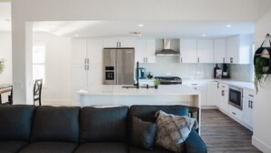 A modern kitchen with white cabinets, a stainless steel refrigerator, and a central island. - Palmeras- Pool, Views, Game Room (Indian Wells)