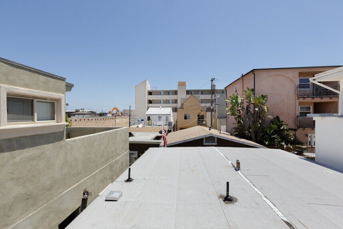 Una terraza en la azotea con techo plano, paredes de hormigón y cielo despejado.