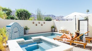 A pool area with a tiled wall, lounge chairs, and a view of mountains.