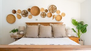 Une chambre à coucher avec un lit en bois, une literie de couleur beige et un mur décoré de paniers tressés.