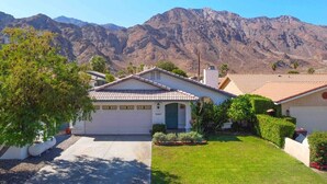 A residential house with a garage, surrounded by a well-maintained lawn and a mountain backdrop. - Desert Rose - Private Pool, Hiking, 3br, #223630 (La Quinta)