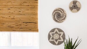 A room with a window covered by a bamboo blind, a wall with three circular woven wall hangings, a potted plant, and a wooden dresser with drawers. - Desert Rose - Private Pool, Hiking, 3br, #223630 (La Quinta)