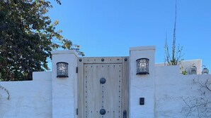 A wooden gate with a metal handle and two lantern-style lights on either side, leading to a concrete pathway.