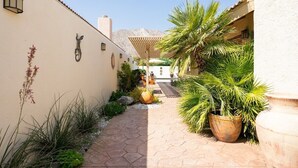 A narrow pathway flanked by potted plants and a building with a tiled roof. - Carranza Cove — Private Pool, LIC #221952 (La Quinta)