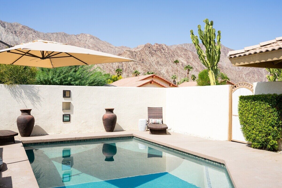 A swimming pool with a clear view of the surrounding desert landscape, including mountains and cacti.
