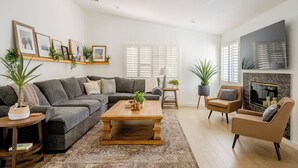 A living room with a gray sectional sofa, a wooden coffee table, a fireplace, and a TV mounted on the wall. - Carranza Cove — Private Pool, LIC #221952 (La Quinta)