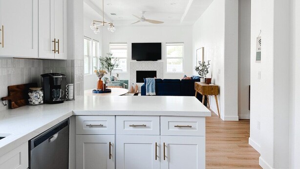 A modern kitchen with white cabinetry, a central island, and a dining area with a blue sofa. - Casita Azul - Resort Amenities, Tennis 2BR260196 (La Quinta)