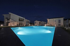 A modern residential complex with a swimming pool at dusk.