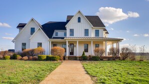 A large, two-story white house with a covered porch and a front walkway. - Rustic Missouri Vacation Rental w/ Hill Views! (Greenfield)