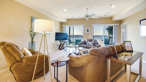 Un salon spacieux avec un canapé, une table basse et un téléviseur. Il y a un balcon avec vue.