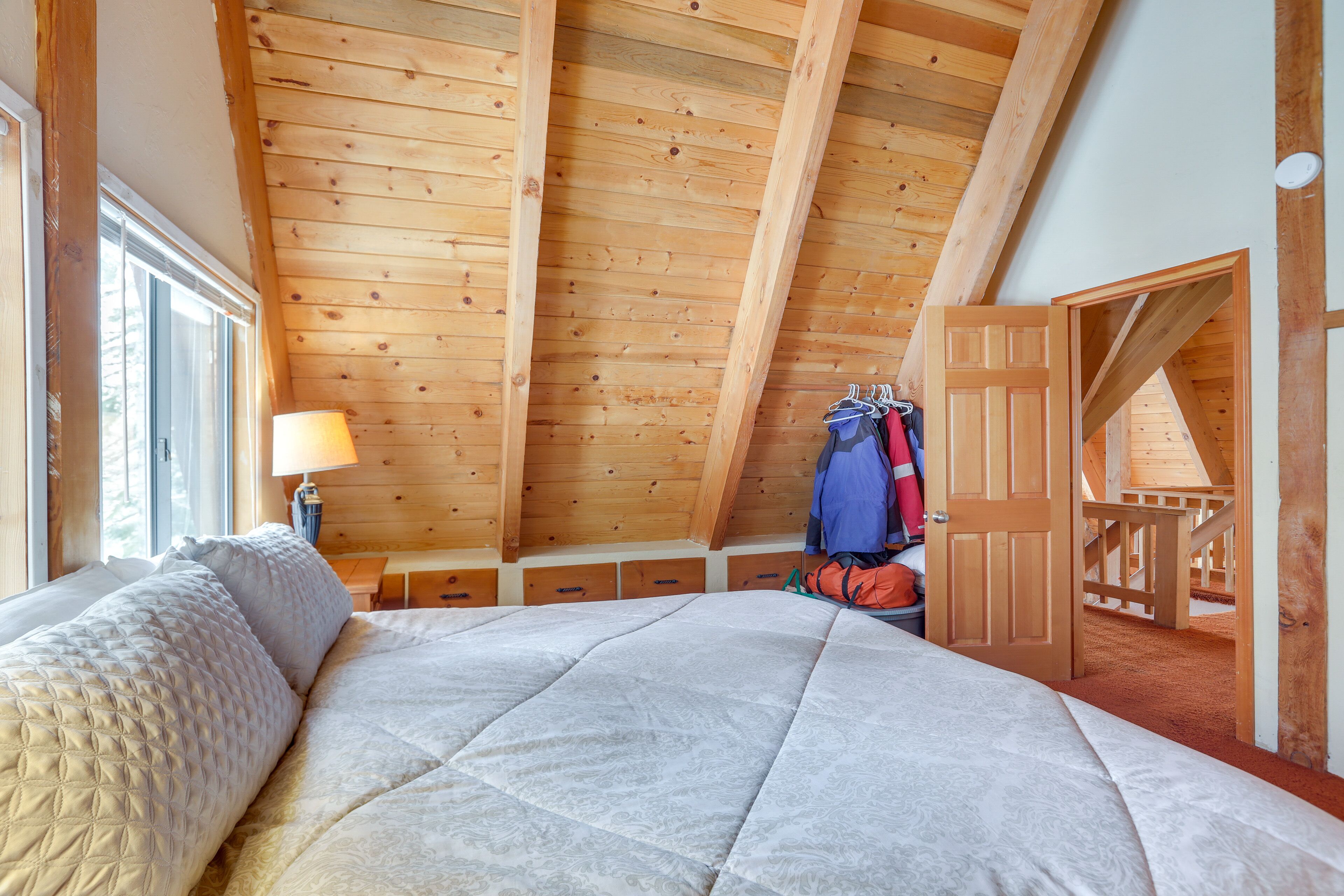 Una camera da letto con un letto grande, travi in legno a soffitto, una finestra e una porta che dà su un balcone.
