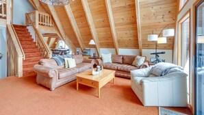 A spacious loft with high ceilings, wooden beams, a staircase, and a cozy seating area with sofas and a coffee table. - Donner Lake Views: Rustic Truckee Cabin! (Truckee)