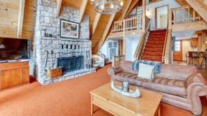 A spacious living area with a stone fireplace, a leather sofa, and a wooden coffee table. - Donner Lake Views: Rustic Truckee Cabin! (Truckee)