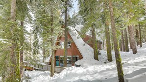A cabin surrounded by tall pine trees with a wooden deck and a snow-covered roof. - Donner Lake Views: Rustic Truckee Cabin! (Truckee)