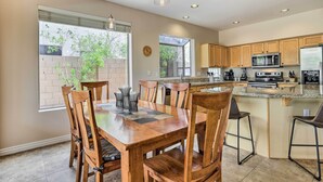 A modern kitchen with wooden cabinets, a central island, and a dining area with a wooden table and chairs. - Private Pool & Yard: Central Cave Creek Retreat! (Cave Creek)