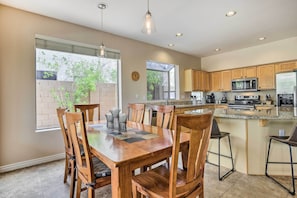 A modern kitchen with wooden cabinets, a large island, and a dining area with a wooden table and chairs.
