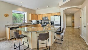 A modern kitchen with a central island, bar stools, and a view of the outdoors. - Private Pool & Yard: Central Cave Creek Retreat! (Cave Creek)