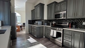 A modern kitchen with grey cabinets, a black and white backsplash, stainless steel appliances, and a wooden floor. - Casita de Tubac (Tubac)