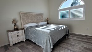 A bedroom with a bed, nightstands, a dresser, and a window with blinds. - Casita de Tubac (Tubac)