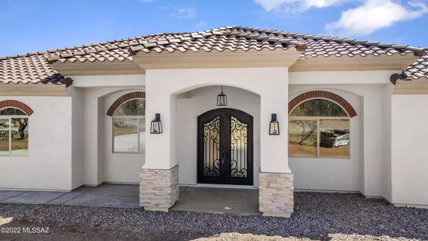 A house with a tiled roof, a central entrance with a decorative door, and two side windows with arched tops. - Casita de Tubac (Tubac)