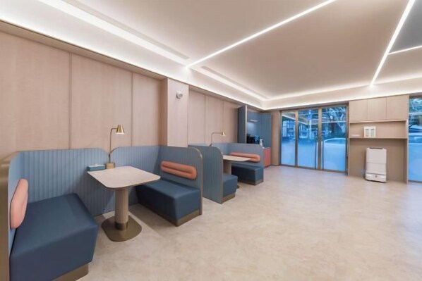A modern interior with seating areas, tables, and a visible refrigerator.