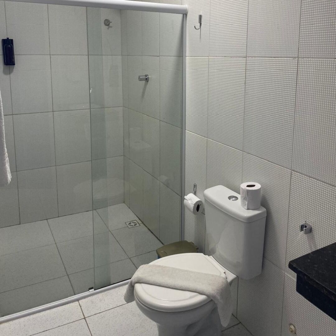 Un baño con cabina de ducha de vidrio, inodoro y encimera negra.