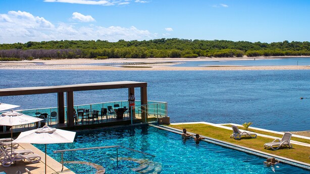 A pool with a view of the sea, surrounded by lounge chairs and umbrellas. - Pousada Jirituba (Barra de Santo Antonio)