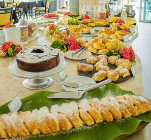 Een buffet met diverse gebakjes, een taart en een fles vruchtensap.