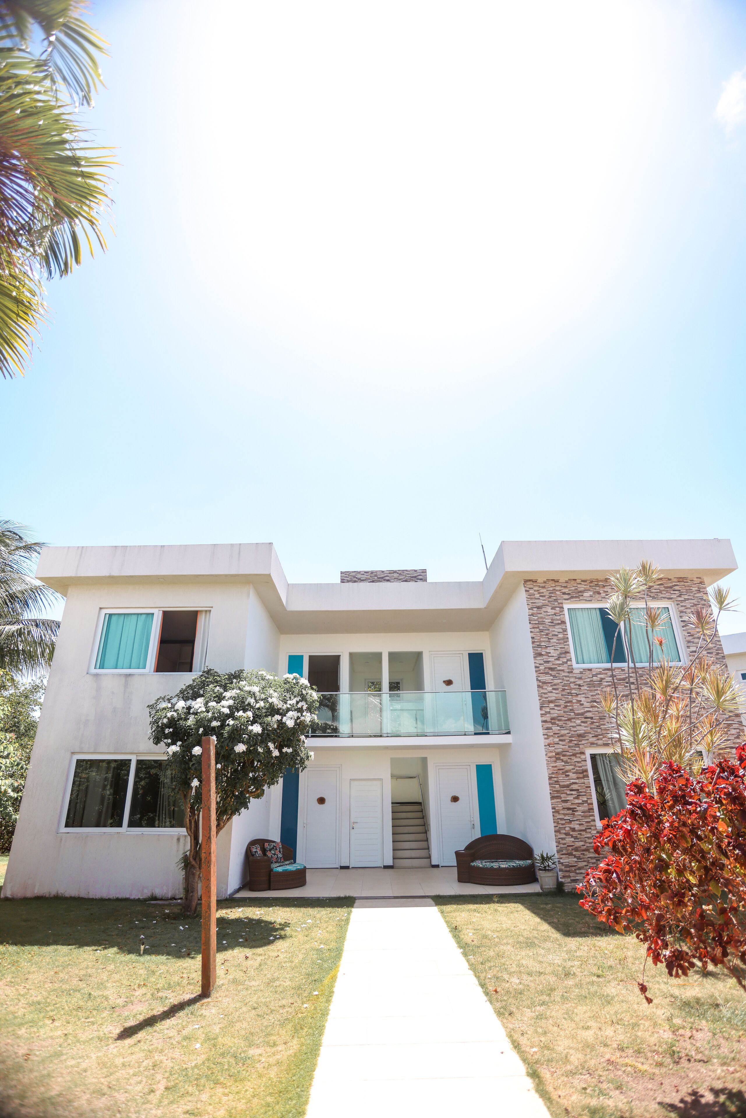 A modern two-story house with a balcony, a front porch, and a well-maintained lawn.