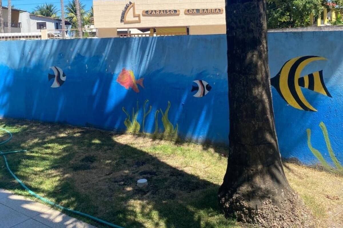 Pared azul con murales de vida marina, una palmera y un edificio con el letrero 'PARAISO DA BARRA'.