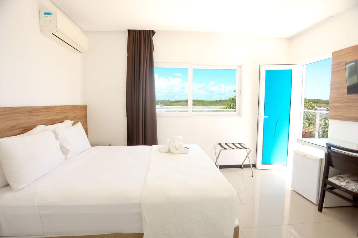 Una habitación de hotel con cama, escritorio, silla, ventana con vistas y puerta.