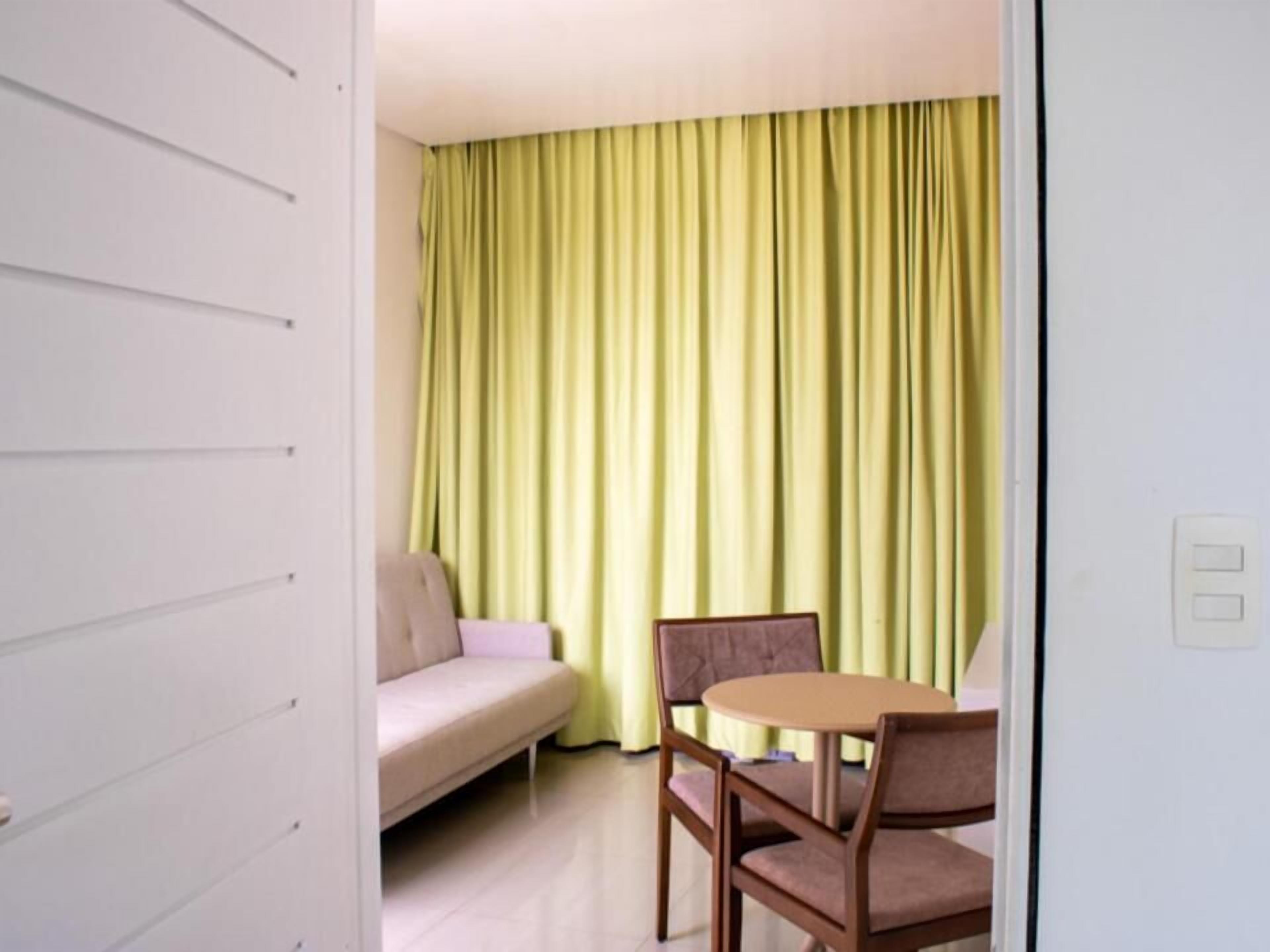 A room with a sofa, two chairs, and a table.