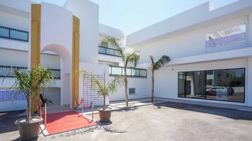 Un edificio moderno con alfombra roja, plantas en macetas y cielo despejado.